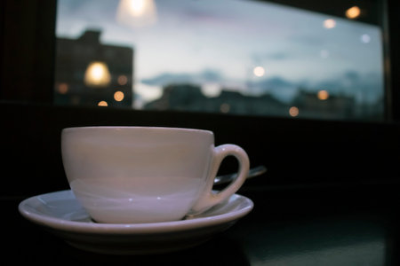Coffee mug by the window in cafe. Bokeh city lights in background.の写真素材