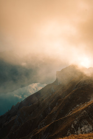 A golden sunset over the mountain and lake covered with fog