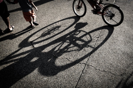 A silhouette of a bicycle giving shade on a asphalt groundの写真素材