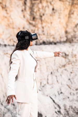 An elegant woman dressed in a white suit using a virtual reality gogglesの写真素材