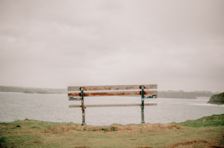 A wooden bench on the Cornish coast under a cloudy skyの写真素材