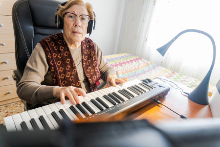 Caucasian elderly woman learning music and playing the musical keyboard.の写真素材