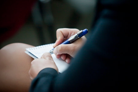 A closeup of a woman writing in a note padの写真素材