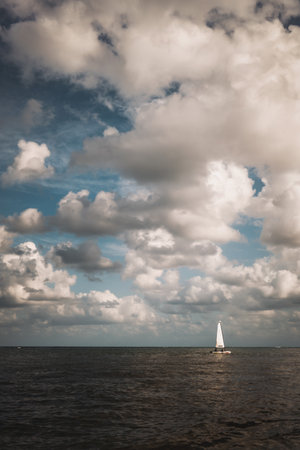 A vertical shot of a boat on the sea with cloudy sky backgroundの写真素材
