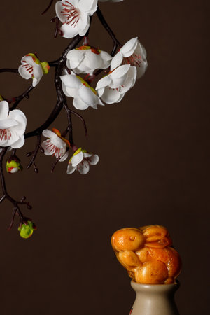 A closeup of a rabbit cookie under a flowering branch on a brown background