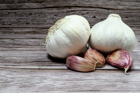 A closeup of fresh garlic cloves on a rough wooden table background