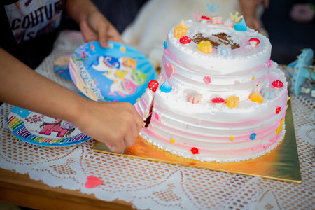 A closeup shot of a person cutting a beautiful decorated cute birthday cake for a little girlの写真素材