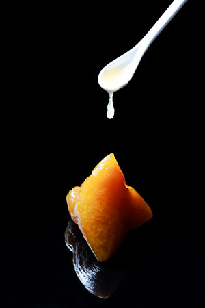 A closeup shot of a White chocolate sauce spoon falling on Zongzi traditional Chinese with black backgroundの写真素材