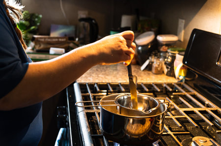 A chef doing a double boiler procedure to melt chocolate in a kitchenの写真素材