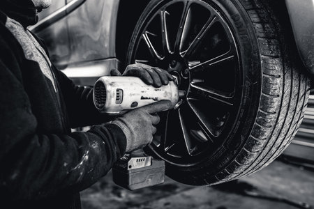 A mechanic undoes an alloy wheel nut to repair itの写真素材
