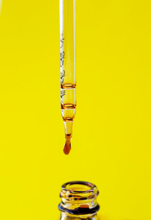 a photo of a pipette with liquid on a yellow backgroundの写真素材