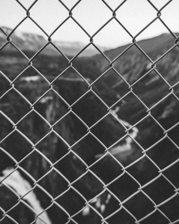 A vertical grayscale view of a metal fence outdoorsの写真素材