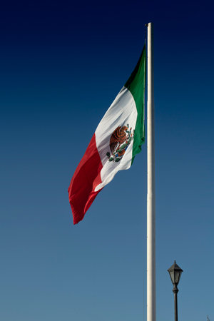 A vertical shot of the flag of Mexico on a blue sky backgroundの写真素材