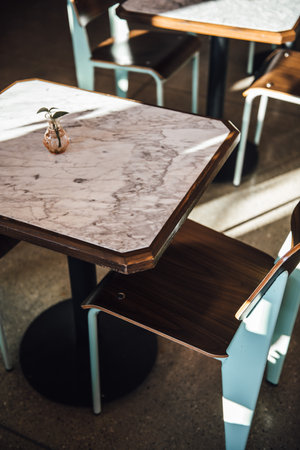 A vertical of a wooden table and a chair with a vase with plant on it.