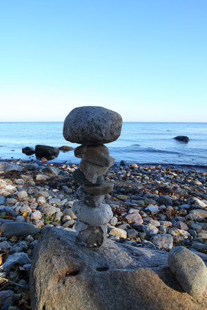 A vertical closeup shot of a tower of stones at the seashore