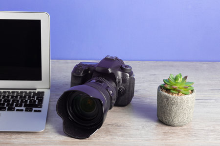 The photographer workstation with a camera, laptop and potted plant on the wooden tableの写真素材