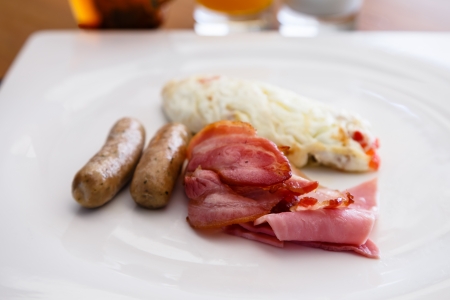 Breakfast dish include white egg omellete bacon and sausageの写真素材