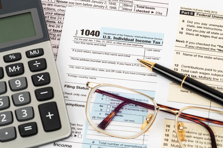 Tax form with pen, calculator, and glasses taxation conceptの写真素材