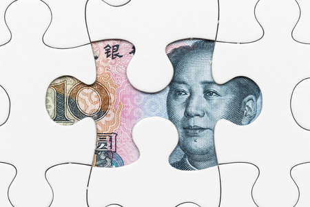 Chinese yuan banknote hidden under puzzle financial conceptの写真素材