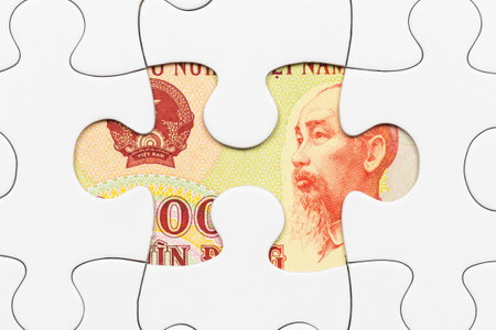 Vietnamese dong banknote hidden under puzzle financial conceptの写真素材