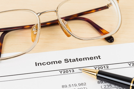 Income statement financial report with glasses and pen