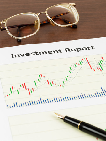 Investment report candle stick chart with pen and glassesの写真素材