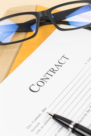 Business contract document with pen and glasses on envelopeの写真素材