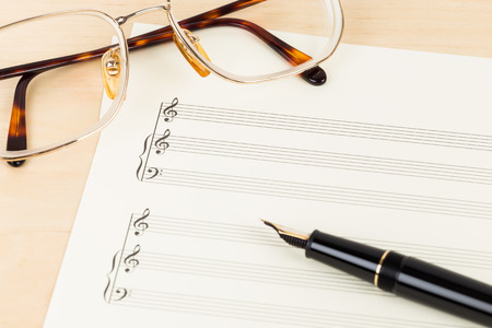 Blank music score on cream color paper with glasses and penの写真素材