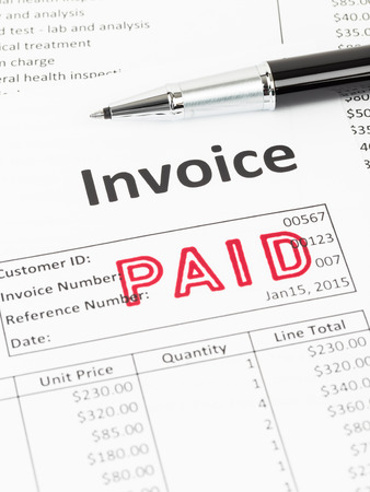 Invoice and pen with paid stamp; document is mock-upの写真素材