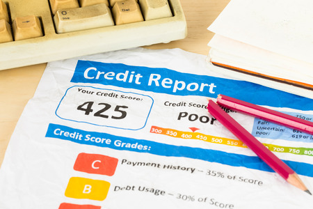Poor credit score report on wrinkled paper with pen and keyboardの写真素材
