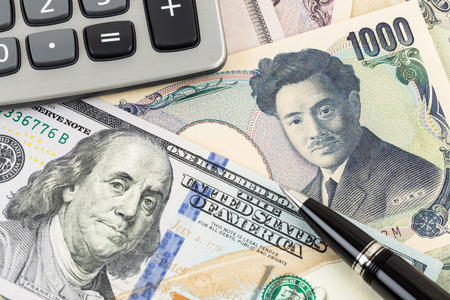 US Dollar and Japanese Yen banknote money with pen and calculatorの写真素材