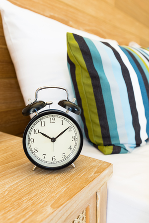 Vintage retro alarm clock on bed side table at 10 o'clockの写真素材