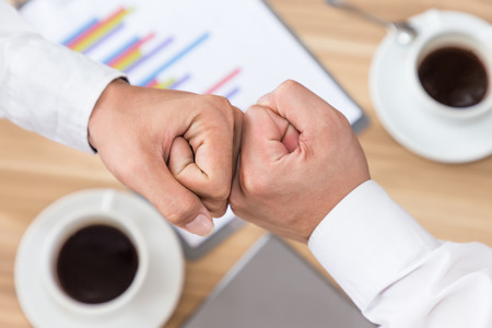 Asian business people giving fist bump successful deal partnership top view