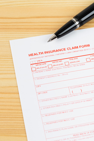 Health insurance claim form with pen on wooden deskの写真素材