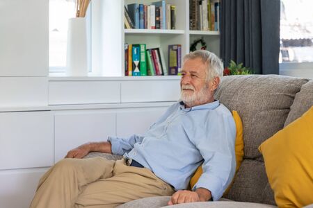 Relax happy senior old man eldery sitting on comfortable sofa in living roomの写真素材
