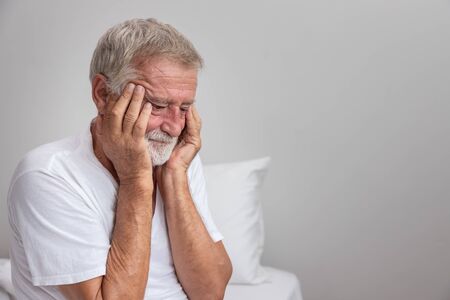 Senior elderly man sitting on bed with depressed after waking up in morningの写真素材