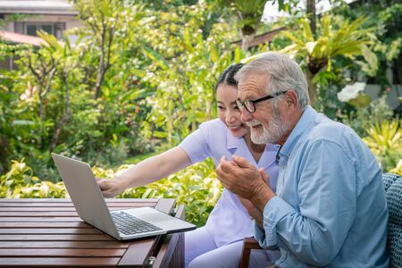 Caregiver assist senoir eldery man using notebook laptop computer connect to Internet