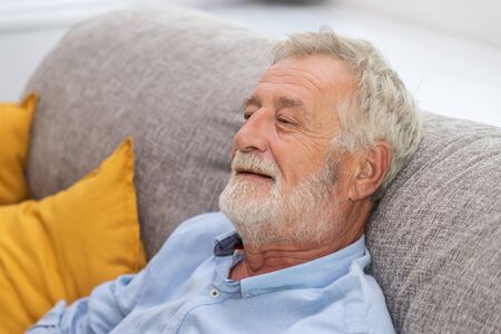 Relax happy senior old man eldery sitting on comfortable sofa in living room