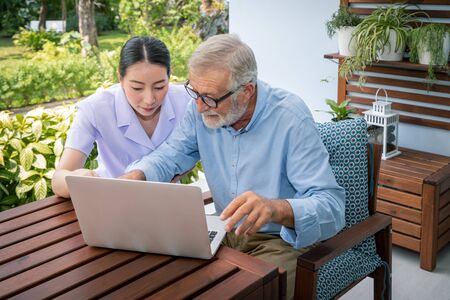 Caregiver assist senoir eldery man using notebook laptop computer connect to Internetの写真素材