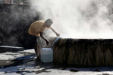 Ranong, Thailand - February 19, 2019: A man collect water from famous hot spring well in Raksa Warin public park.のeditorial素材