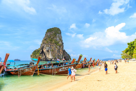 Krabi, Thailand - February 16, 2020: Long tail boat and turquoise crystal clear sea water with limestone cliff and mountain at Phra Nang Beach.のeditorial素材