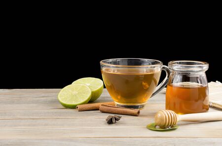 Early morning tea cups with lemon and honey resting on an old wooden table on a black backgroundの写真素材