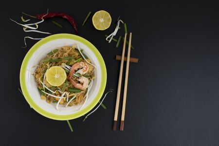Thai food, Pad Thai, fresh prawns and lime lemons, vegetables on the table, black backgroundの写真素材