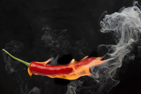 Red chilli with flame, black background, the concept of spicy - picturesの写真素材