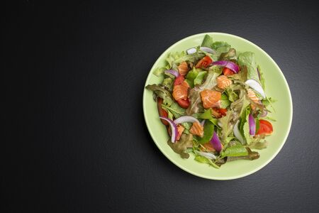 Fresh salmon salad with tomatoes Fresh green onions and vegetables On a black backgroundの写真素材