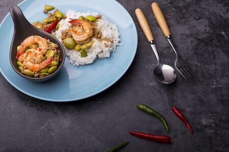 Bitter bean stir-fried with fresh shrimp or Sato fried shrimp in a blue dish Placed on a black tableの写真素材