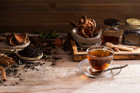 eacup with saucers and a variety of herbs arranged on a wooden spoon and honey Placed on a black table background is an old wooden wall And a faint sun shining from behindの写真素材