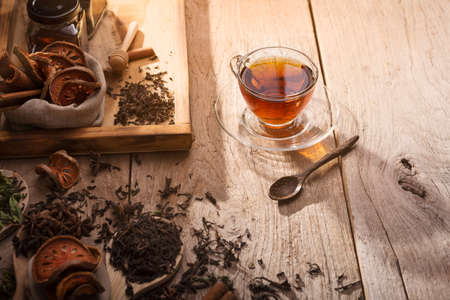 teacup with saucers and assorted herbs and honey are placed on the old wooden table top and the...