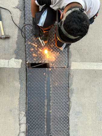 staff welder is doing maintenance on the damaged cutter rails on the road.