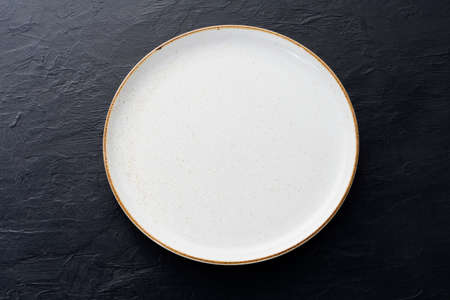 Empty white ceramic plates with spoons and forks arranged on an old black wooden table - top view.の写真素材